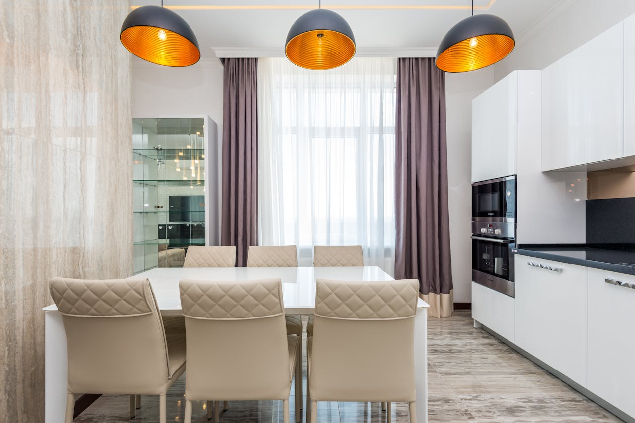 A modern dining room featuring elegant chairs, a white table, and contemporary lighting.