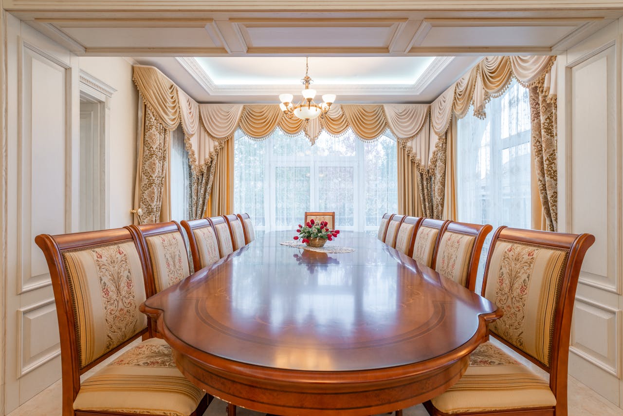 A beautifully decorated dining room featuring a long wooden table and ornate curtains, exuding elegance and luxury.